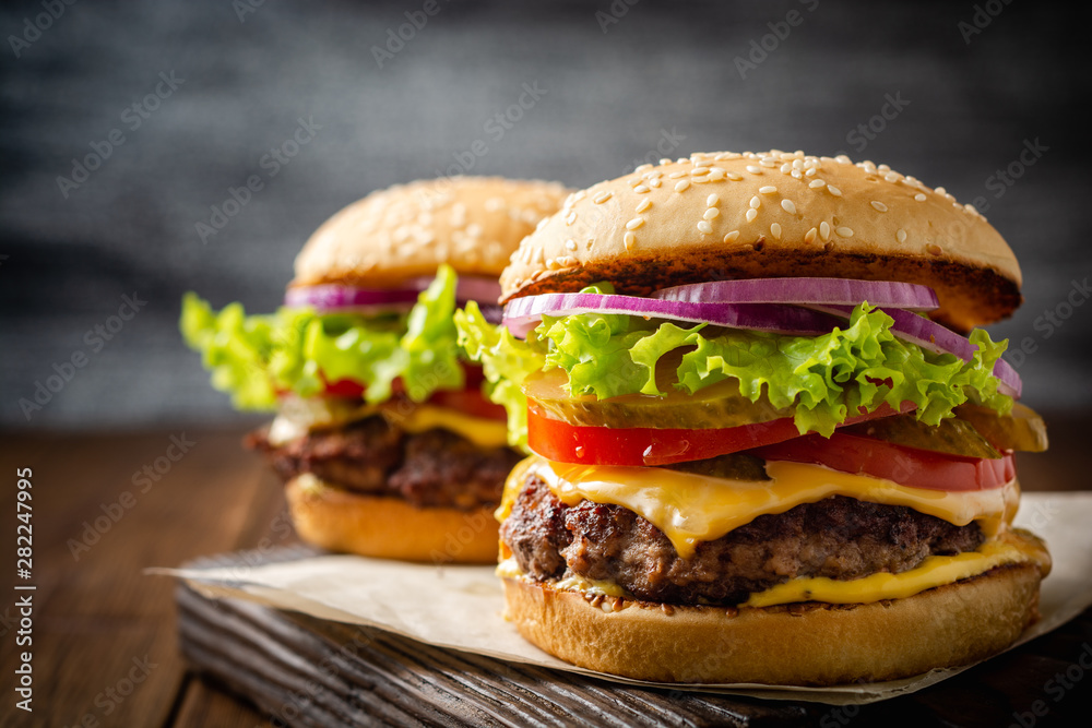 Two homemade tasty burgers on wood table. Selective focus. - obrazy, fototapety, plakaty 