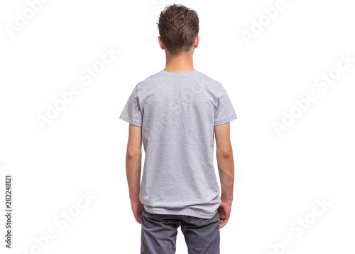 T-shirt design concept. Teen boy in blank gray T-shirt, isolated on white background - back view. Mock up template for print. Child with hands in pockets - rear view.