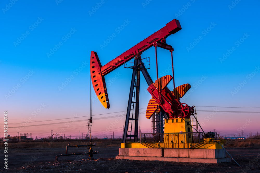 Oil pumps are running at different angles at sunset in oil field. Oil pumps are running at different angles at sunset in oil field.