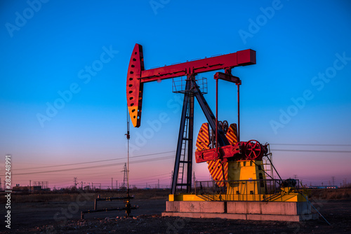 Oil pumps are running at different angles at sunset in oil field.