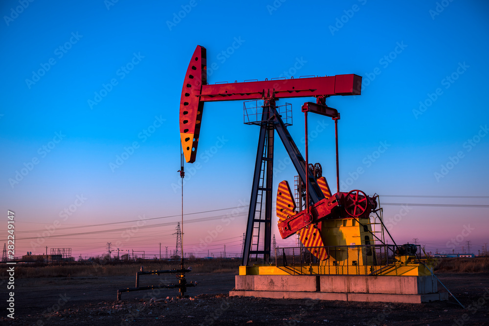 Oil pumps are running at different angles at sunset in oil field. Oil pumps are running at different angles at sunset in oil field.