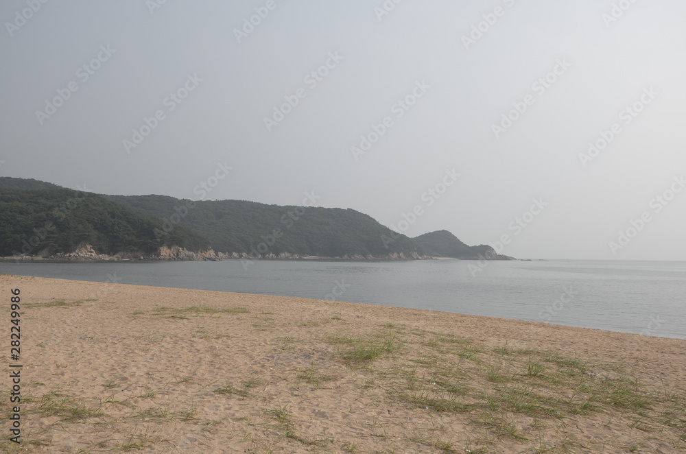 A picture of Tranquil summer beach on a slightly hazy day. 