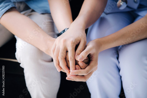 Friendly female doctor holding male patient's hand for encouragement and empathy.