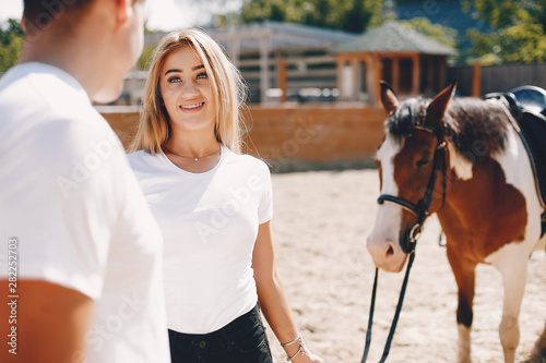 Cute couple with a horses. Lady in a white t-shirt. Pair in a summer park © prostooleh