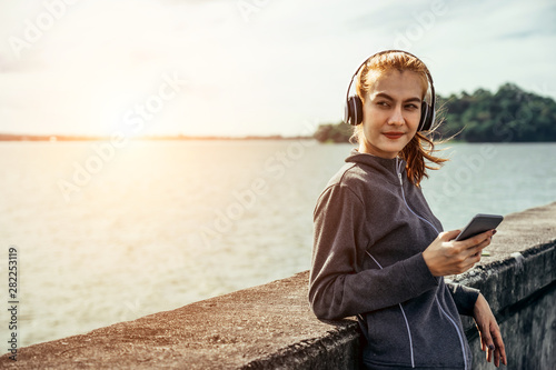 Asian woman is workout and running at the morning, She listening the music from her smart-phone. Healty and sport lifestyle concept.