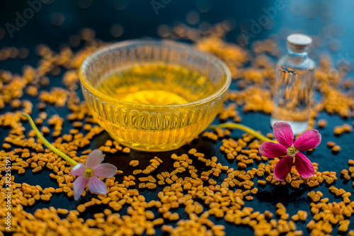 Raw fenugreek seeds on the wooden surface with some coconut oil and its paste in a glass bowl used as the remedy of dandruff.Famous natural method.