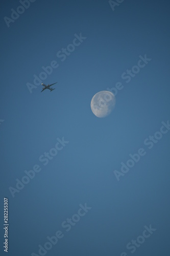 Aeroplane and the moon in a blue sky background