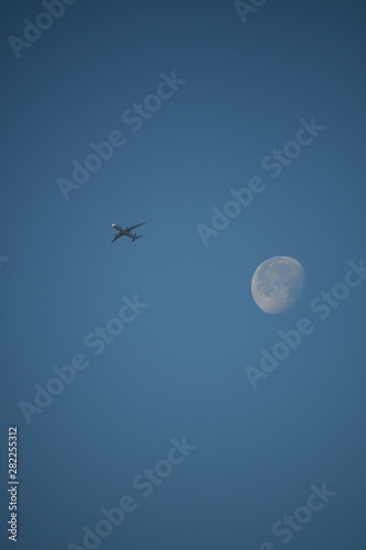 Aeroplane and the moon in a blue sky background