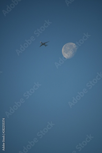 Aeroplane and the moon in a blue sky background