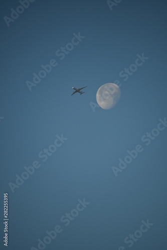 Aeroplane and the moon in a blue sky background