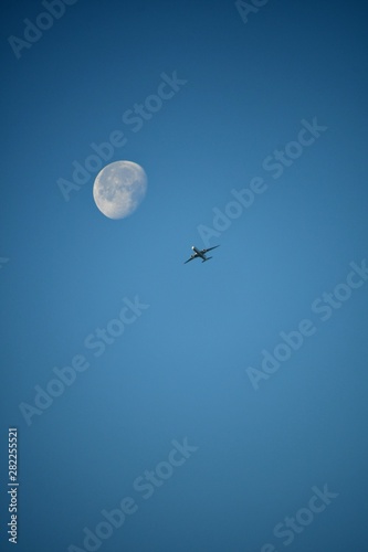 Aeroplane and the moon in a blue sky background