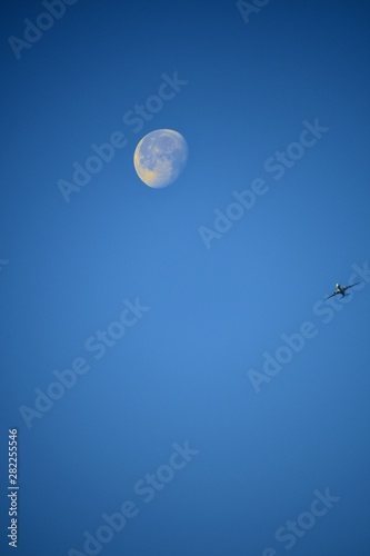 Aeroplane and the moon in a blue sky background