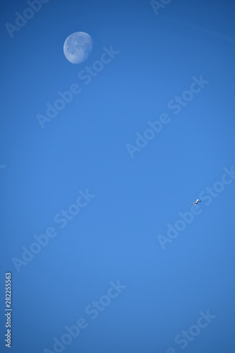 Aeroplane and the moon in a blue sky background