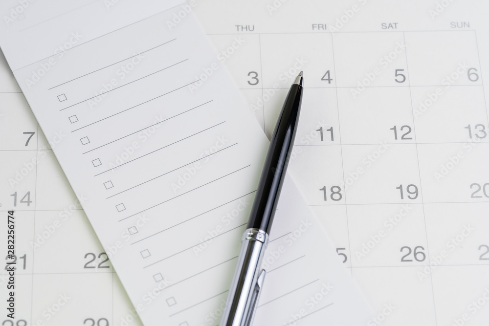 Pen on checklist with checkbox notepad on clean calendar using as special event, planner, important reminder or appointment list concept Pen on checklist with checkbox notepad on clean calendar using as special event, planner, important reminder or appointment list concept