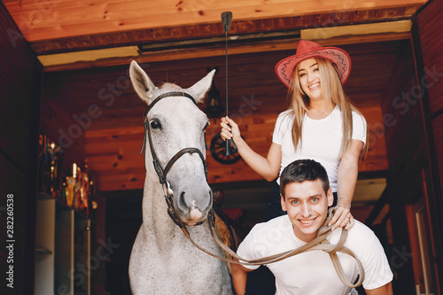Cute couple with a horses. Lady in a white t-shirt. Pair in a summer park