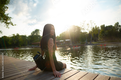      Girl sitting on pier and lookingat the river                photo