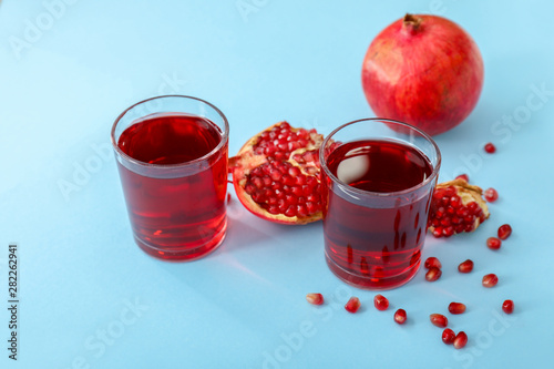 Glasses of fresh pomegranate juice on color background