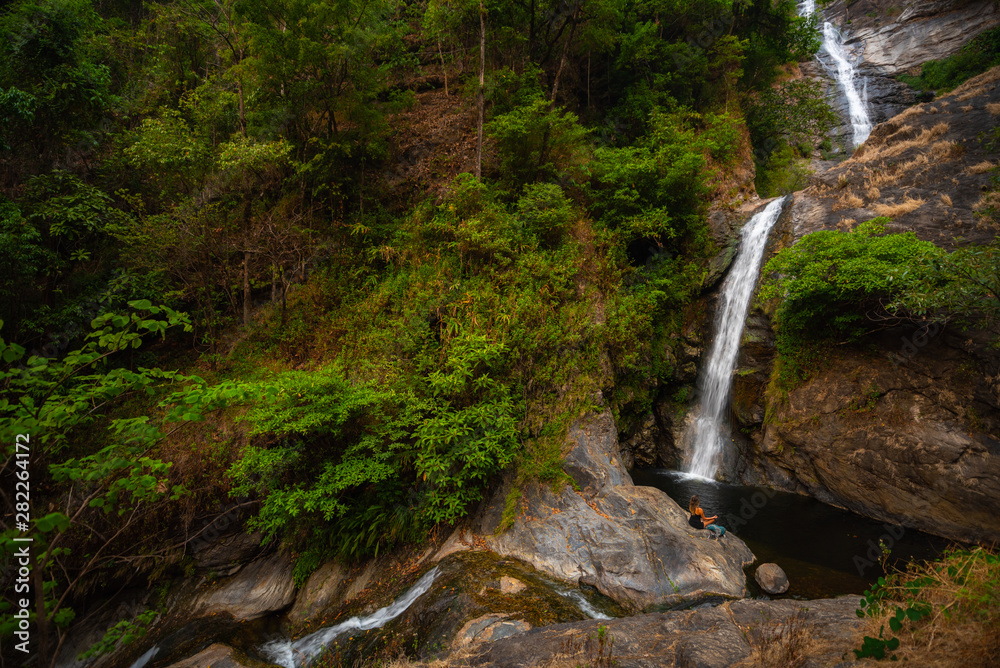 Woman practicing meditation in nature by Mae Pan waterfall in Doi Inthanon National Park