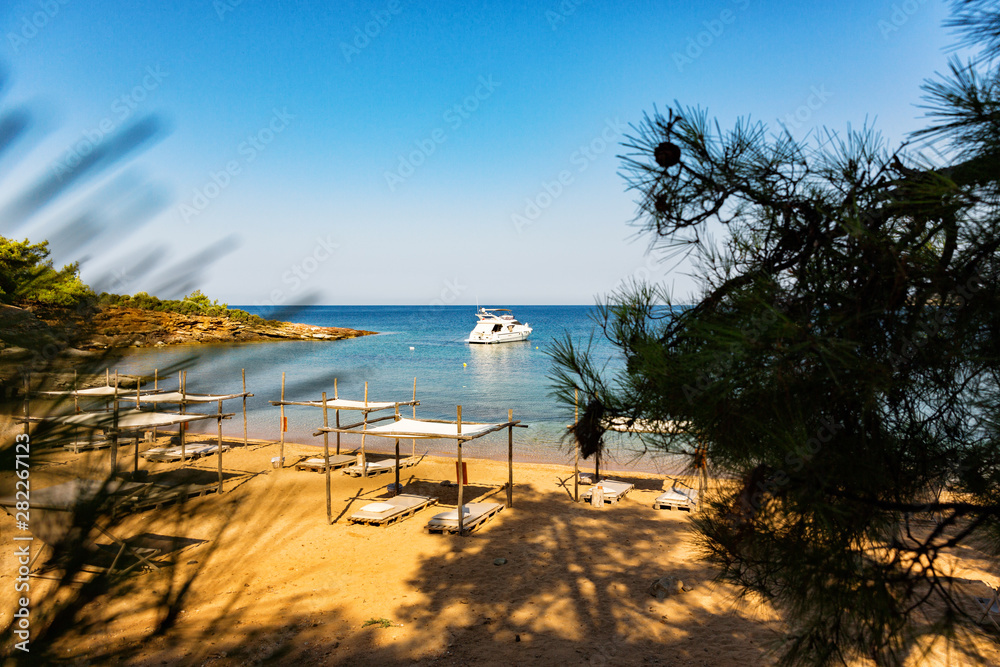 Beautiful mediterranean sandy beach with yacht on the sea horizon.