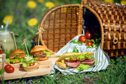 Sandwiches and a snack near to a picnic basket on a sunny day.