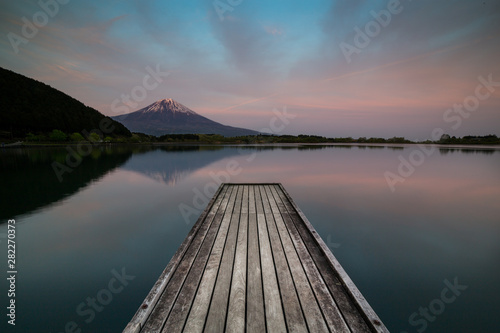 Wooden pier on Tanukiko Lake in front of Mount fuji at sunset