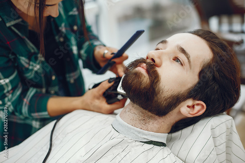 Man with a beard. Hairdresser with a client. Woman with a comb and shaving machine