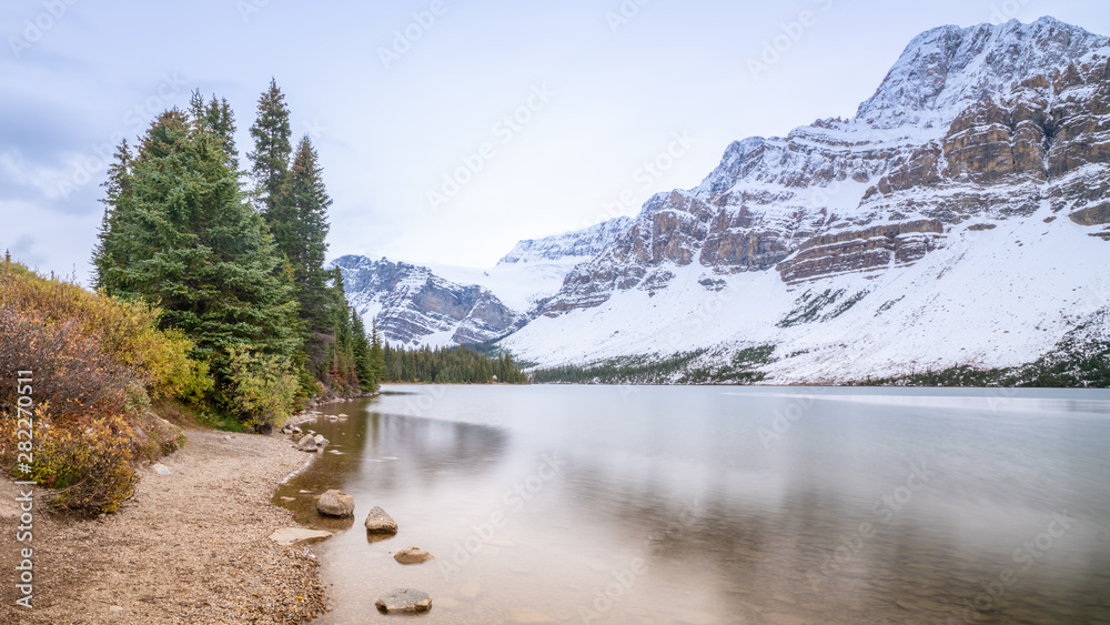 Long exposure photography of Bow lake with green pine forest on the shore, Banff National park, Alberta, Canada