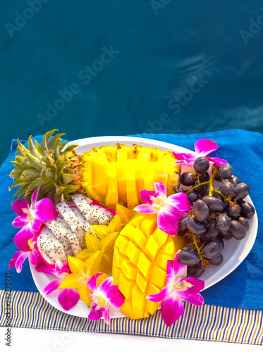 Fruit plate with delicious and fresh local asian pineapple, mango, grapes and dragon fruit (pitaya or pitahaya) on the luxury sailing yacht on a cruise between Phuket and Phi Phi islands, Thailand