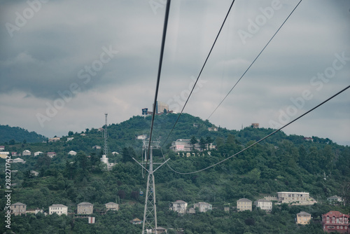 view from the cabin of the cable car to the houses built on the mountainside. in cloudy weather with clouds in the sky.