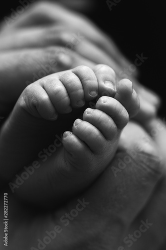 Little foot of a newborn baby on a black background close-up © tatyaby