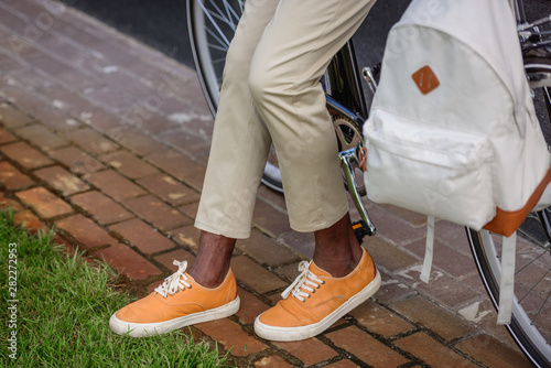 cropped view of stylish african american man standing near bicycle with backpack
