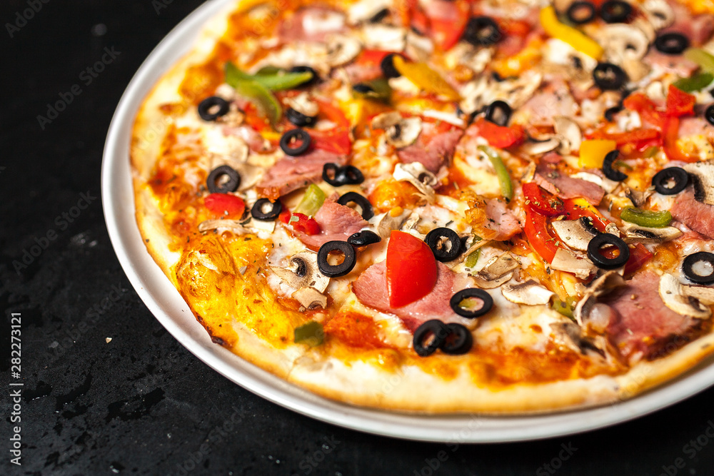 Close-up of a pizza with olives mushrooms with meat and tomatoes Close-up of a pizza with olives mushrooms with meat and tomatoes