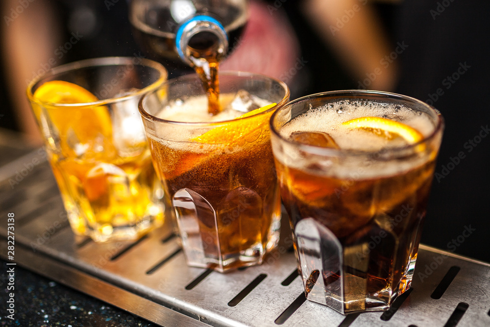 Close-up of expert bartender making cocktail in bar, splash of whiskey and cola. Close-up of expert bartender making cocktail in bar, splash of whiskey and cola.