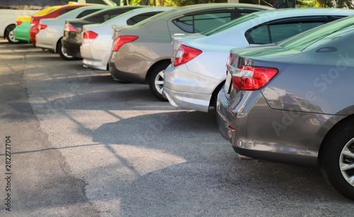 Closeup of rear, back side of grey blue car with other cars parking in outdoor parking lot in sunny day. 