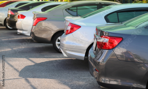 Closeup of rear, back side of grey blue car with other cars parking in outdoor parking lot in sunny day. 