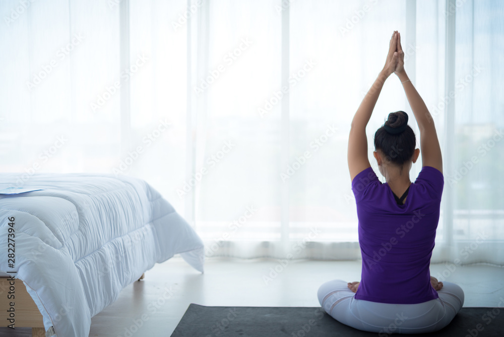A beautiful young woman sitting in a yoga room in a calm and relaxed manner. Light, comfortable, light window background comes in the morning. Health care concepts A beautiful young woman sitting in a yoga room in a calm and relaxed manner. Light, comfortable, light window background comes in the morning. Health care concepts