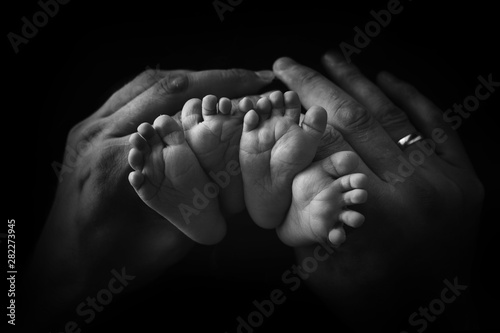 Little foot of a newborn baby on a black background close-up