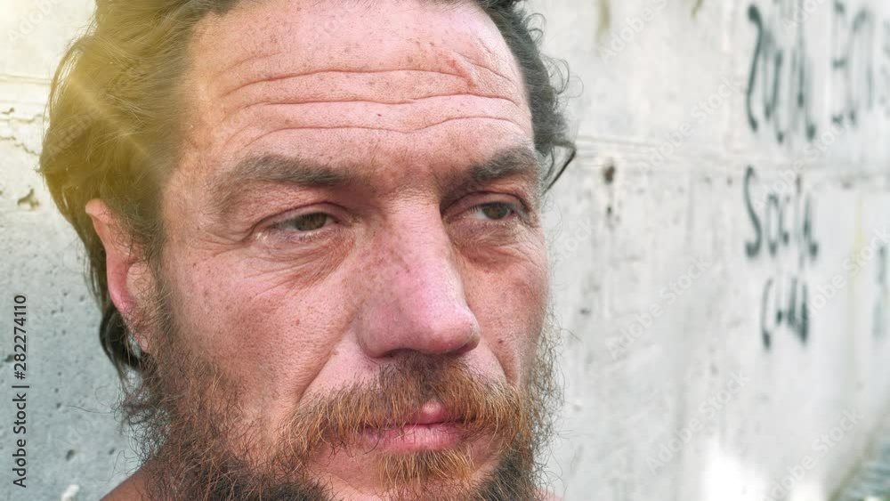 Slow motion close-up face of real homeless man. Real person with no fixed abode. Down-and-out person on the street. Degraded man looks at the camera, social degradation Slow motion close-up face of real homeless man. Real person with no fixed abode. Down-and-out person on the street. Degraded man looks at the camera, social degradation