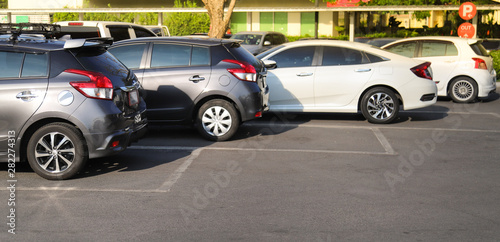 Closeup of rear, back side of brown car with  other cars parking in outdoor parking lot in bright sunny day.  © Amphon