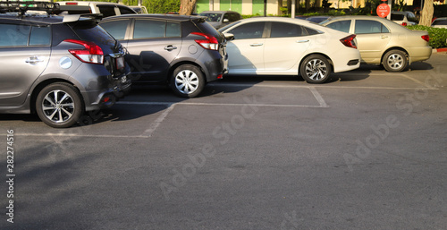 Closeup of rear, back side of brown car with other cars parking in outdoor parking lot in bright sunny day. 