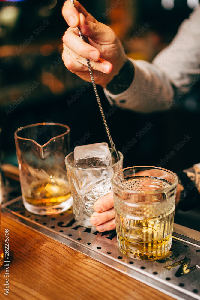 Close-up of expert bartender making cocktail on the bar, blurred background. Close-up of expert bartender making cocktail on the bar, blurred background.