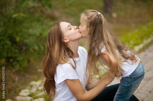 Happy smiling mother and daughter child are kissing and having fun outdoor in nature © Алина Троева
