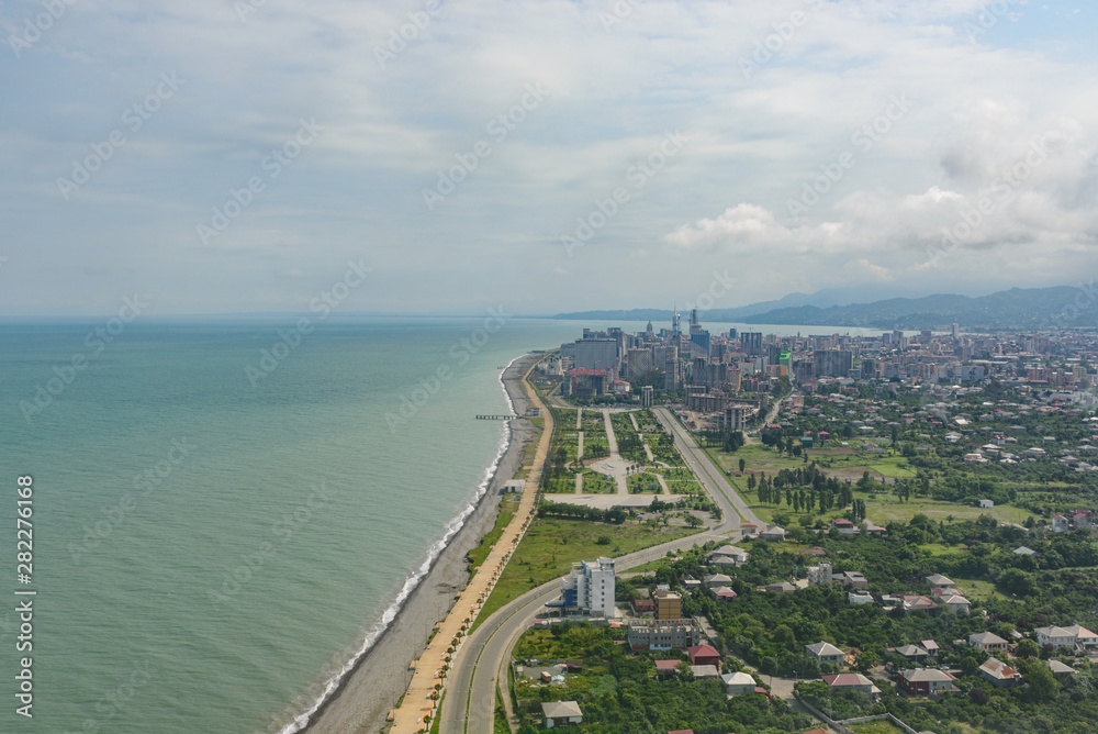 view from the airplane porthole to the resort town of Batumi located in Georgia, on a sunny day with clouds in the sky.