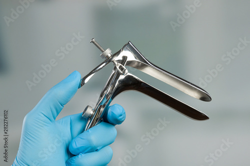 doctor's hand in medical gloves holds a medical speculum