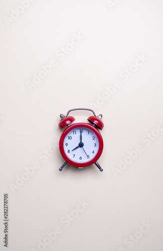 Red alarm clock on light pastel background. Blank note for text. Reminder. Space for copy. Minimal concept.