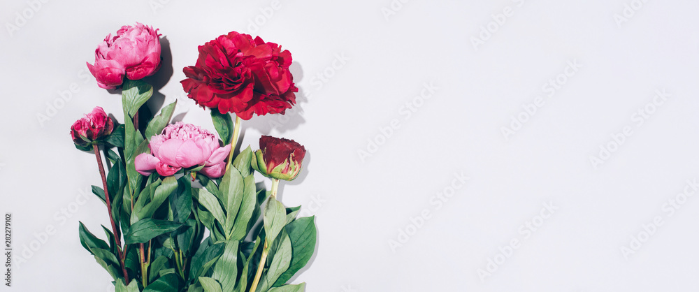 Pink peonies and leaves with hard shadow on pastel background, copy space. Trendy pattern, summer concept. Top view.