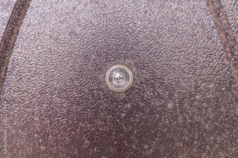 Peephole on the old brown door. Old metal door with a peephole Peephole on the old brown door. Old metal door with a peephole