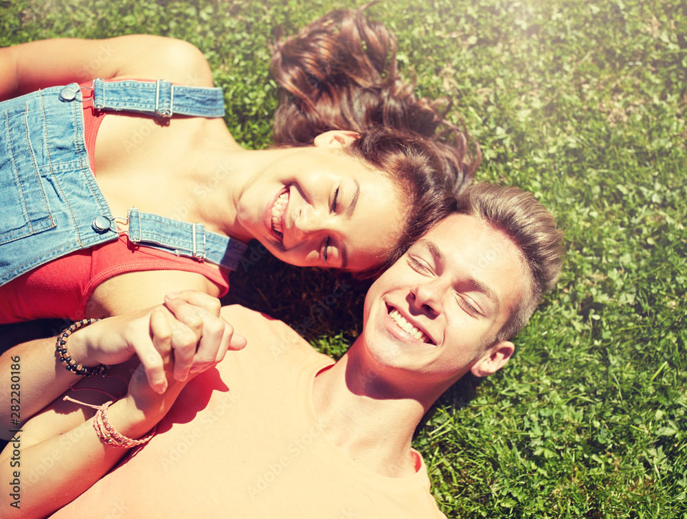 love and people concept - happy teenage couple lying on grass at summer love and people concept - happy teenage couple lying on grass at summer