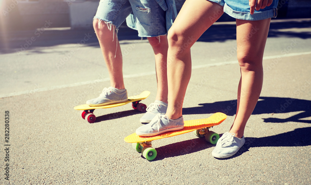 Fototapeta premium summer, extreme sport and people concept - teenage couple riding short modern cruiser skateboards on city street