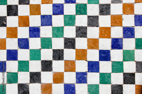 Middle eastern decorative mosaic tile pattern with white, orange, blue, green and black square tiles